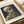 Edgy memento mori poster featuring a human skull with cigarette in impressionist style, rich with burnt sienna and charcoal tones against cream background.