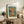 Sunflower arrangement in a ceramic vase, painted in Van Gogh's expressive Impressionist style with vibrant golds, dusty rose accents, and deep blue background, framed as wall art.