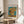 Van Gogh's beloved sunflower composition featuring twelve blooms in golden and ochre yellows with warm rose undertones, set in a simple vase against a contemplative teal backdrop.
