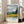 Moody impressionist poster showing a wheat field in golden tones with emerald cypress trees, slate mountains, and an emotionally turbulent sky with sweeping brushwork.