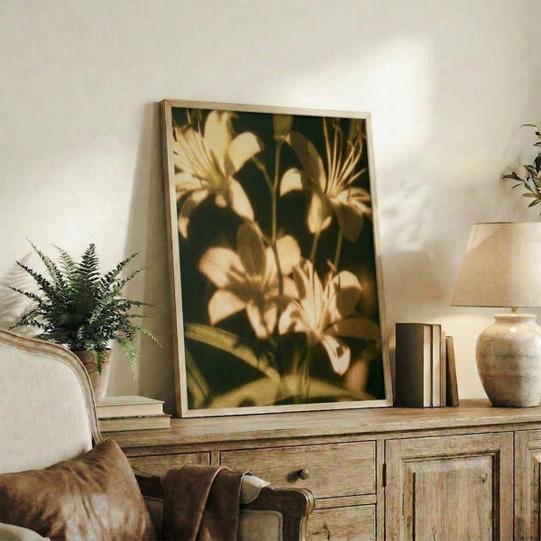 Antique-style botanical art print featuring delicate lilies in muted gold and cream tones with naturalistic stems and leaves, creating a tranquil, timeless aesthetic.