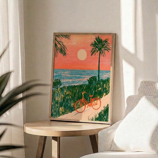 Retro beach poster print showing a bicycle silhouetted against a golden sunset, surrounded by dunes, palm trees, and ocean in forest green, cream, and coral hues.