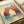Dreamy seascape wall art featuring a classic sailboat beneath towering natural stone arch, nostalgic color palette of mint green, turquoise, cream, and rust tones.