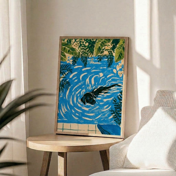 Art nouveau framed wall poster featuring a swimming black Labrador among botanical elements in cobalt blue, cream, and olive green with a cheerful vintage aesthetic.