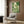 Cottagecore-inspired framed poster depicting a tranquil garden arrangement with ceramic teapot, delicate flowers, lush plants, and perched bird in soothing forest green and cream palette.