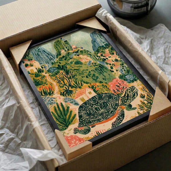 Whimsical cottage-core inspired wall art depicting a tortoise journeying through a hillside village landscape with warm cream, coral, and golden yellow hues against slate blue mountain slopes.