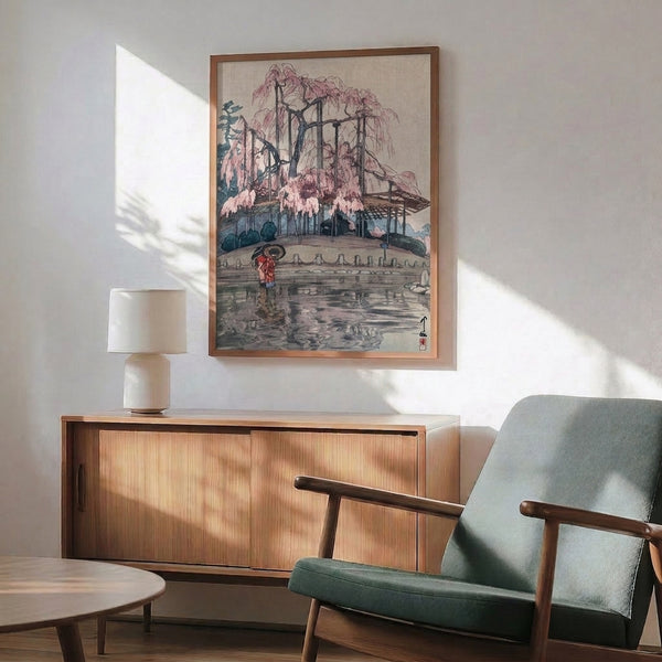 Japandi wall art print in woodblock style: a graceful weeping willow frames a garden pond scene with a figure holding an umbrella, rendered in soft blues, blush tones, and dark accents.