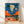 Bold retro pop art poster featuring a weathered bull skull centered against a vibrant orange desert sunset, with saguaro cacti, a crescent moon, and gold accents in deep blue and teal tones.