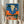Vintage-inspired poster blending cowboy aesthetics with pop art design, depicting a skull and desert landscape in striking orange and teal hues with southwestern cultural imagery.