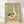 Whimsical folk art print of a silly goose with a heart-shaped wing, surrounded by flowers and leaves in sage green, cream, terracotta, and olive tones, framed on a wall.