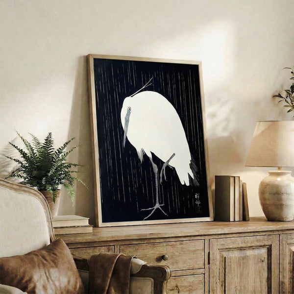 Contemplative bird art print in framed woodblock style, capturing a crane sheltering in rain on a delicate branch with serene linework in cool tones.