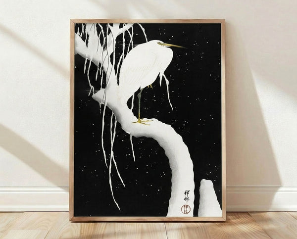 Framed Japanese woodblock print of a white egret perched on a snowy branch with icicles hanging beneath, against a dark night sky dotted with gold stars, rendered in serene minimalist style.