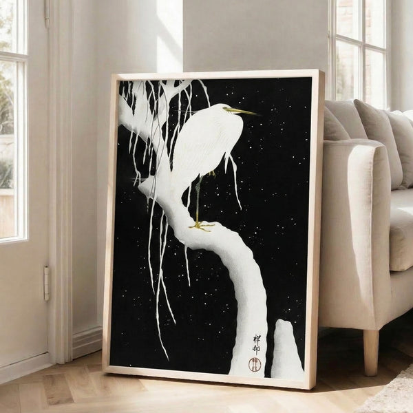 Framed Japandi art print depicting a solitary egret on a snowy branch with icicles, set against a starlit night in cream, black, and gold tones; peaceful and minimalist composition.