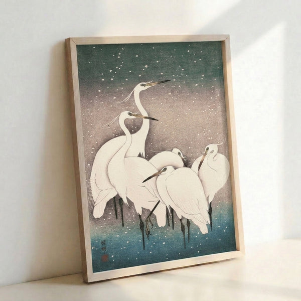 Peaceful winter scene with white herons amid falling snow in traditional Japanese art style, showcasing delicate brushwork in soft sage and slate tones with teal accents.
