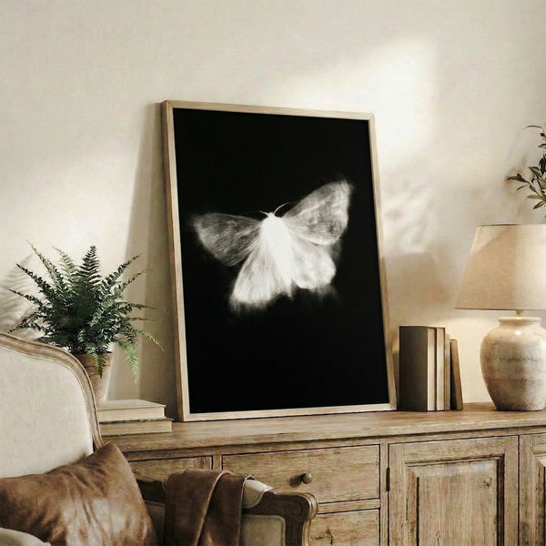 Framed black and white poster of a luminous moth with flowing, graceful line work in a modern minimalist style, perfect for zen-inspired decor.