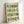 Contemporary wall art print showing stylized wine bottles in playful pop art aesthetic, combining warm oranges and yellows with deep forest green tones.
