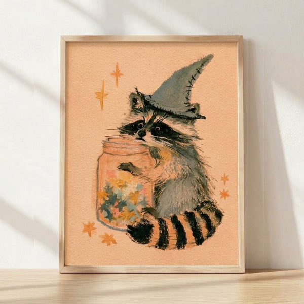 Whimsical watercolor painting of a raccoon wearing a pointed witch hat, surrounded by magical stars and a potion jar, rendered in warm peach, sage green, and golden tones with black accents on a cream background.
