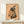 Gothic-inspired watercolor artwork featuring an enchanting raccoon in witchy attire with a tall hat, mystical elements, and celestial details in a palette of peach, sage, and warm gold hues.