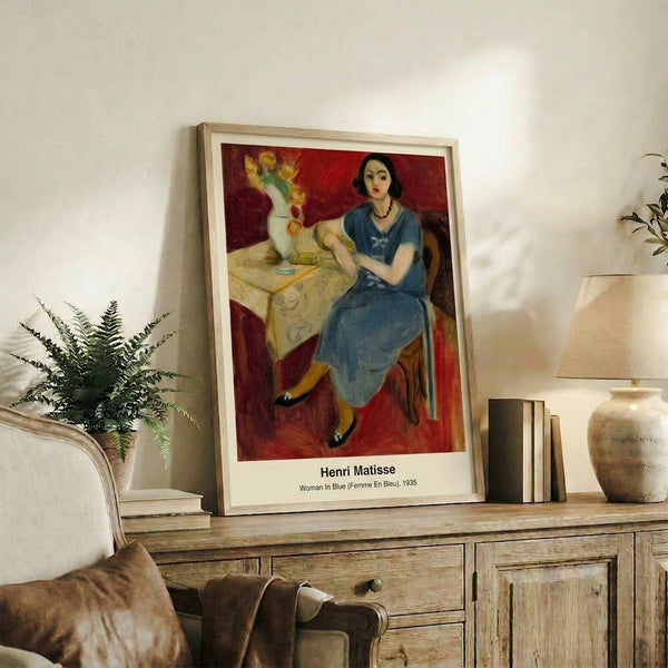 Contemporary framed print inspired by Matisse showing a stylized female figure in blue, white, and ochre with serene, introspective expression and clean geometric forms.
