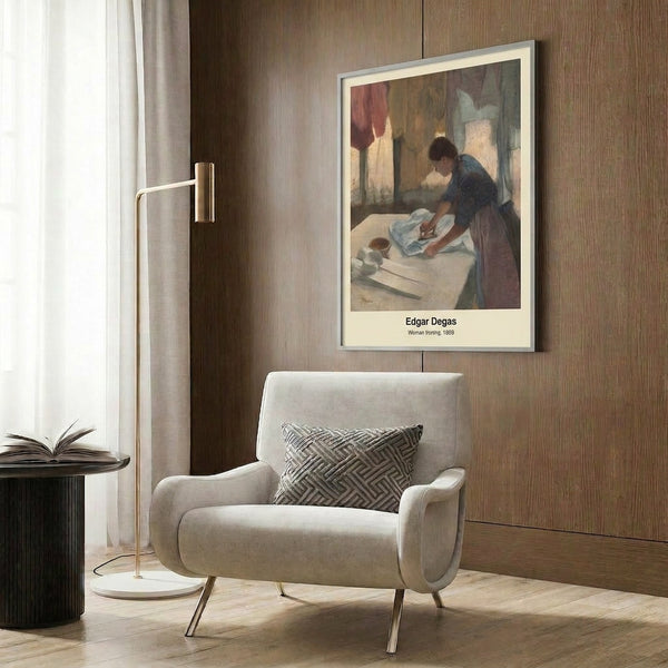 Framed poster art from the Impressionist era showing a solitary woman focused on ironing, composed in warm ochre and cream hues with touches of muted green throughout.