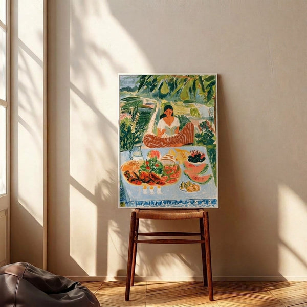 Framed Impressionist poster featuring a serene garden picnic with a reading woman, scattered fruit and bread, leafy botanicals, and a harmonious palette of sage, gold, and soft orange hues.