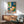 Minimalist living room art print featuring a cozy scene of someone in a reading nook with tulips, books, and a plant, in soothing Japandi-inspired earth tones and blues.
