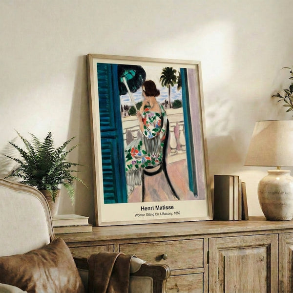 Framed poster of an abstract woman seated on a balcony, characterized by bold colors, minimalist composition, and emotionally expressive brushwork.