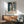 Abstract artwork featuring a woman sitting on a balcony in a bold minimalist style, palette of ochre, blue, green, and black evoking contemplative emotion.