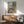 Art print capturing a contemplative interior with a figure and open window, glowing in warm and cool color contrasts of yellow, blue, pink, and green.