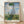 Impressionist painting of a woman holding a parasol in a sunlit field with a child and wildflowers, rendered in soft blues, greens, and creams.