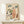 Framed Japanese woodblock print in cream and sage green depicting a woman and cow in a serene countryside scene with woven baskets and folkloric charm.