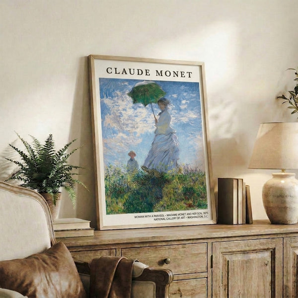 Vintage impressionist framed print showing an elegant woman with parasol accompanying a child through a flower-strewn field beneath a luminous sky in pale blues and greens.