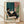Minimalist line drawing of a woman seated in a chair holding a wine glass, rendered in teal, cream, and terracotta tones with a potted plant nearby, framed poster art with calm, sophisticated aesthetic.