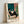 Modern minimalist framed art print showing a contemplative woman with wine seated near botanical elements, executed in soft teal and terracotta hues with clean geometric composition.