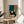 Minimalist living room poster featuring a seated figure with wine glass in teal and terracotta linework, balanced with botanical form, creating a calm and meditative wall art piece.
