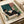 Contemporary minimalist framed poster depicting a woman seated with wine glass near a plant, executed in terracotta, teal, and forest green tones with serene, contemplative mood.