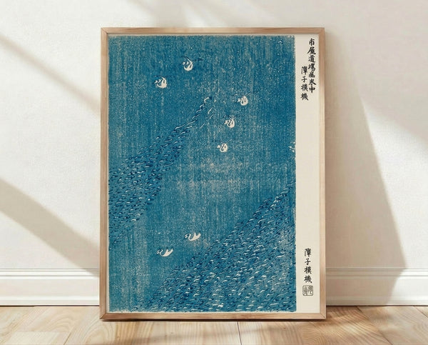 Serene Japanese woodblock print featuring birds among reeds and windswept waves in teal, cream, and blue-gray tones, framed as wall art.
