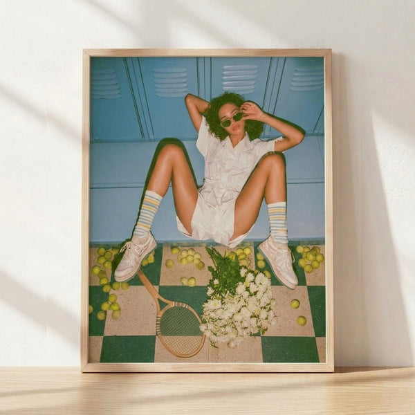 Y2K pop art poster featuring a stylish woman with tennis racket, sunglasses, and vibrant fruit and floral elements in cyan, cream, and yellow-green tones, framed on a wall.