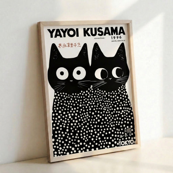 Framed print showing black cats with intricate white polka-dot details and expressive eyes against cream background, combining contemporary minimalism with Japanese woodblock sensibilities.