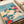Japandi wall art featuring a contemplative yellow bird composition with blooming red peonies, layered green leaves, and a soothing turquoise and cream color palette.