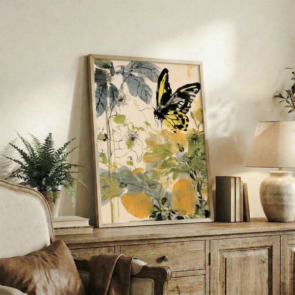 Delicate watercolor garden scene featuring a yellow swallowtail butterfly with soft flowers, leaves, and vines in cream, yellow, and grey-blue hues, hung as framed wall art.