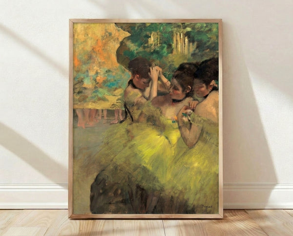 Framed Degas painting of ballet dancers in yellow tutus backstage, rendered in soft pastels with muted blue and ochre tones, capturing an intimate moment of grace and movement.